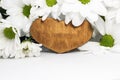 On a white background among a bouquet of white chrysanthemums a wooden heart with a place for the text