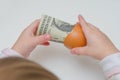 A child took a dollar in an egg shell on white background Royalty Free Stock Photo