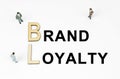 On a white background, figures of businessmen, wooden letters and the inscription - BRAND LOYALTY