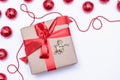 On a white background, a gift with a red ribbon and an angel next to the red Christmas balls. Festive postcard Royalty Free Stock Photo