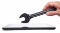 In this white background, a hand and a black wrench emerge from a digital tablet screen. The concept is of technical Royalty Free Stock Photo