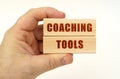 On a white background, a hand that holds wooden blocks with the inscription - Coaching Tools