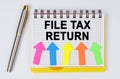 On a white background lie a pen and a notebook with the inscription - FILE TAX RETURN Royalty Free Stock Photo