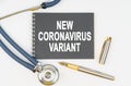 On a white background lie a stethoscope, a pen and a notebook with the inscription - NEW CORONAVIRUS VARIANT Royalty Free Stock Photo