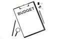 On a white background magnifier, a pen and a sheet of paper with the text BUDGET . Business concept Royalty Free Stock Photo