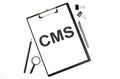 On a white background magnifier, a pen and a sheet of paper with the text CMS . Business concept Royalty Free Stock Photo