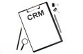 On a white background magnifier, a pen and a sheet of paper with the text CRM .Business concept Royalty Free Stock Photo