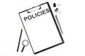 On a white background magnifier, a pen and a sheet of paper with the text POLICIES . Business concept Royalty Free Stock Photo