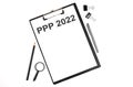 On a white background magnifier, a pen and a sheet of paper with the text PPP 2022 . Business concept Royalty Free Stock Photo