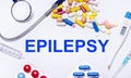 On a white background pills, stethoscope, syringe, thermometer and text EPILEPSY. Medical concept