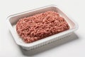 On a white background, a plastic tray holds raw, fresh, minced beef