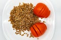 Two ripe red tomatoes and buckwheat with Flax seed oil are on a white plate Royalty Free Stock Photo