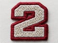 White background with a red and white collegiate style embroidered patch number 2 Subtle paper texture, vibrant red thread Royalty Free Stock Photo