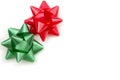 White background with red and green traditional Christmas adhesive gift bows in upper left corner