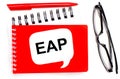 On a white background, white and red notepads, black glasses, a red pen and a white card with the text EAP Employee Assistance Royalty Free Stock Photo