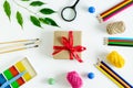 on a white background, a set of stationery, pencils, thread, paint brushes, plasticine and a gift with a red ribbon. Royalty Free Stock Photo