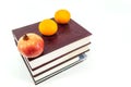 Fresh fruit on the books. One pomegranate and two mandarins Royalty Free Stock Photo