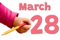 White background with spring red date, business and holiday concept. The child`s hand writes March 28 with colored pencil