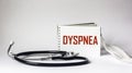 On a white background, a stethoscope, a medical mask and a notepad with the word Dyspnea Royalty Free Stock Photo