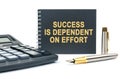 On a white background, there is a calculator and a black notebook with the inscription - SUCCESS IS DEPENDENT ON EFFORT