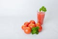 On a white background tomatoes, a glass of juice and a bunch of parsley, concept, freshly squeezed juice, natural