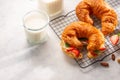 On a white background, two mouth-watering croissants with fresh strawberries and green mint leaves and milk. French breakfast for Royalty Free Stock Photo