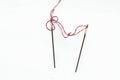 On a white background two sewing needles connected by a red thread Royalty Free Stock Photo