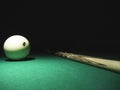 White ball number 8 from russian billiard pyramid and a cue on a table. Black background