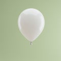 A white balloon floats against a solid light green background. The balloon is smooth a Royalty Free Stock Photo