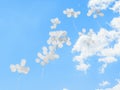 White balloons fly into the sky with clouds.