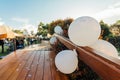 White balloons hanging around a wooden bridge the floor is sprinkled with roses. People come to congratulate the couple,