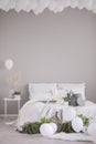 White balloons under the ceiling of stylish grey bedroom with comfortable bed, real photo with