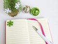 White ballpoint pen on the opened notebook in a pink cover and Christmas balls on a white background, Christmas and New Year ideas