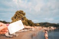 White Bank Card In Woman Hand On Background Of Hotel Beach, Family Comes Out Of Sea, Moraitika, Corfu, Greece. The Concept Of