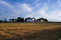 White barn with golden field and blue sky with white clouds Royalty Free Stock Photo