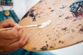 White is always the base paint. an unrecognizable artist dipping her paintbrush into white paint during an art session