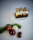 On white base a piece of cake on a white plate and christmas decoration