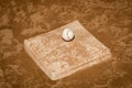 Image of a baseball on a dirt covered third base.