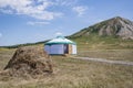 White Bashkir yurt stands between a haystack and a mountain