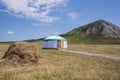 White Bashkir yurt stands between a haystack and a mountain