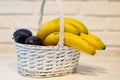 White basket with bananas and plums