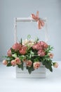 White basket with a bouquet of pink artisanal roses. Pink bow on a wooden handle Royalty Free Stock Photo
