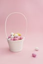 White basket with Easter chocolate multicolored eggs