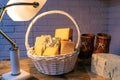 A white basket filled with various cheeses against a brick wall. Aged cheese is illuminated by a table lamp Royalty Free Stock Photo