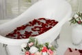 White bath with rose petals. Taking a bath with roses.