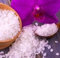 White bath salt in a wooden cup with a spoon on a wooden table with an orchid Royalty Free Stock Photo