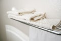 White bath towels lying on a shelf in an ordinary home light bathroom with beige tiles with copy space, shower and every