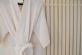 White bathrobe on a hanger on the wall Royalty Free Stock Photo