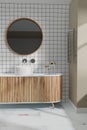 White bathroom wiith stylish round mirror over wash basin and small white square tiles on wall