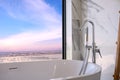 White bathtub near the window, overlooking the beach, Sunset landscape outside scenery. Luxury master bathroom interior Royalty Free Stock Photo